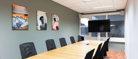 A conference room with a long table, black chairs, and artwork on the walls.