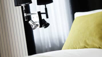 A hotel room with a bed, a nightstand, and a lamp.