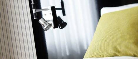 A hotel room with a bed, a nightstand, and a lamp.