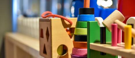 Una estructura de madera para juegos con bloques de colores y una casita.
