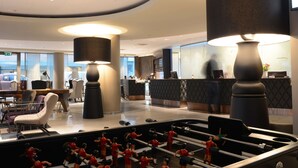 A modern lobby with a reception desk, seating area, and large lamps. - Scandic Bergen City (Bergen)