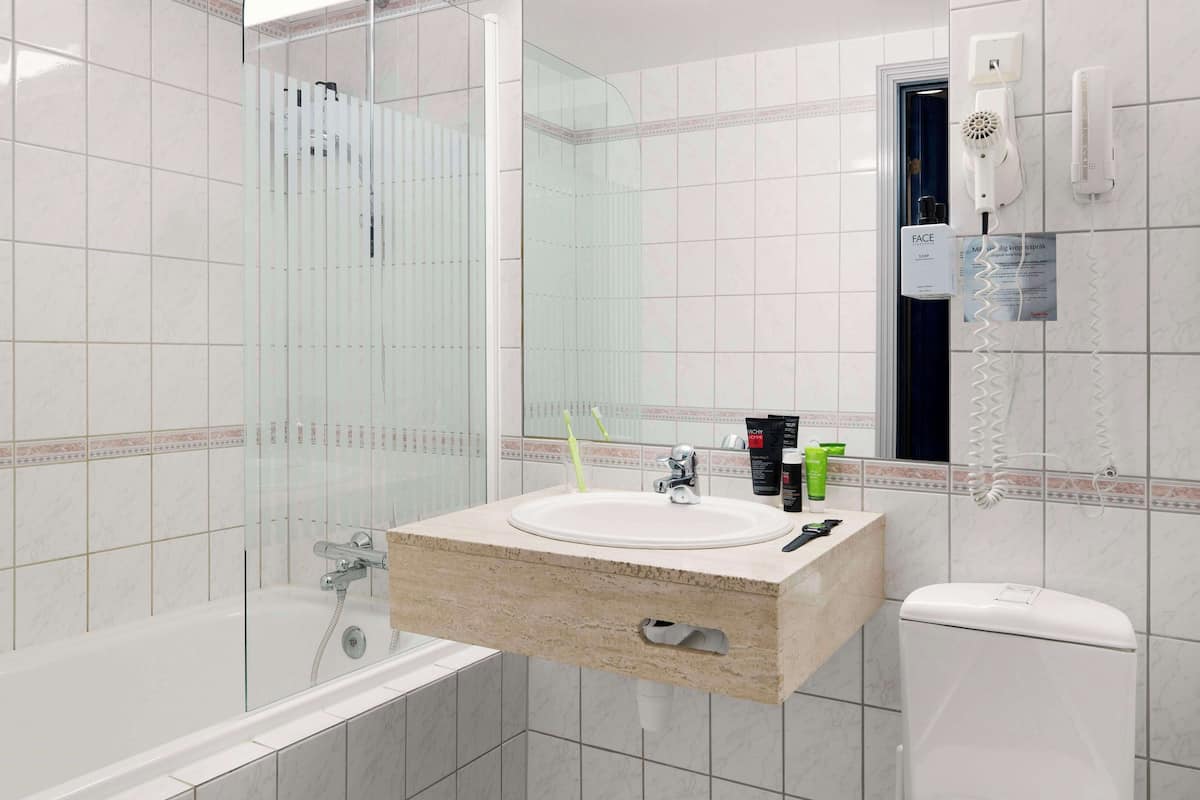 Een moderne badkamer met een douchecabine van glas, een wastafel met toiletartikelen en een toilet.