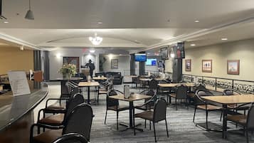A hotel lobby with a reception desk, seating area, and a TV screen displaying a menu.
