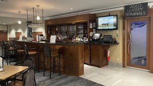 A bar area with a counter, seating, and a television screen displaying a video lottery terminal. - Victoria Inn Hotel and Convention Centre Winnipeg (Winnipeg)