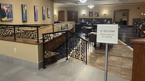 A spacious restaurant with high ceilings, chandeliers, and artwork on the walls. - Victoria Inn Hotel and Convention Centre Winnipeg (Winnipeg)