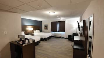 Une chambre d’hôtel avec un lit, un bureau, une chaise, une télévision et une fenêtre avec des rideaux.