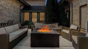 Un espace extérieur aménagé avec un foyer, du mobilier de jardin et un bâtiment en briques.