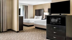 Une chambre d’hôtel avec deux lits, une télévision, un four à micro-ondes et une commode.