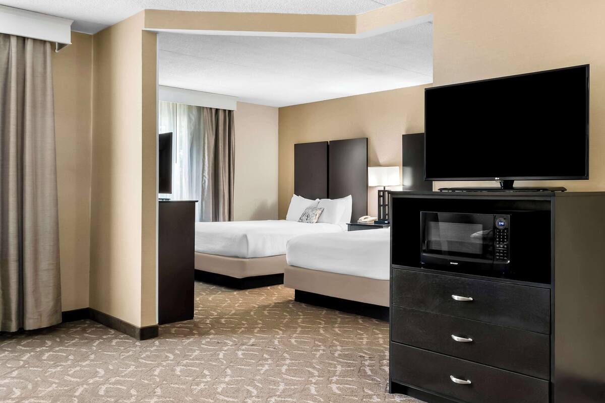 Een hotelkamer met twee bedden, een televisie, een magnetron en een dressoir.