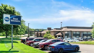 Un parking d’hôtel Best Western avec plusieurs voitures et un panneau indicateur.