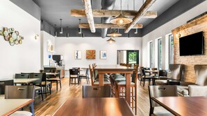 Un restaurant moderne avec des tables et des chaises en bois, un bar et un grand écran de télévision.