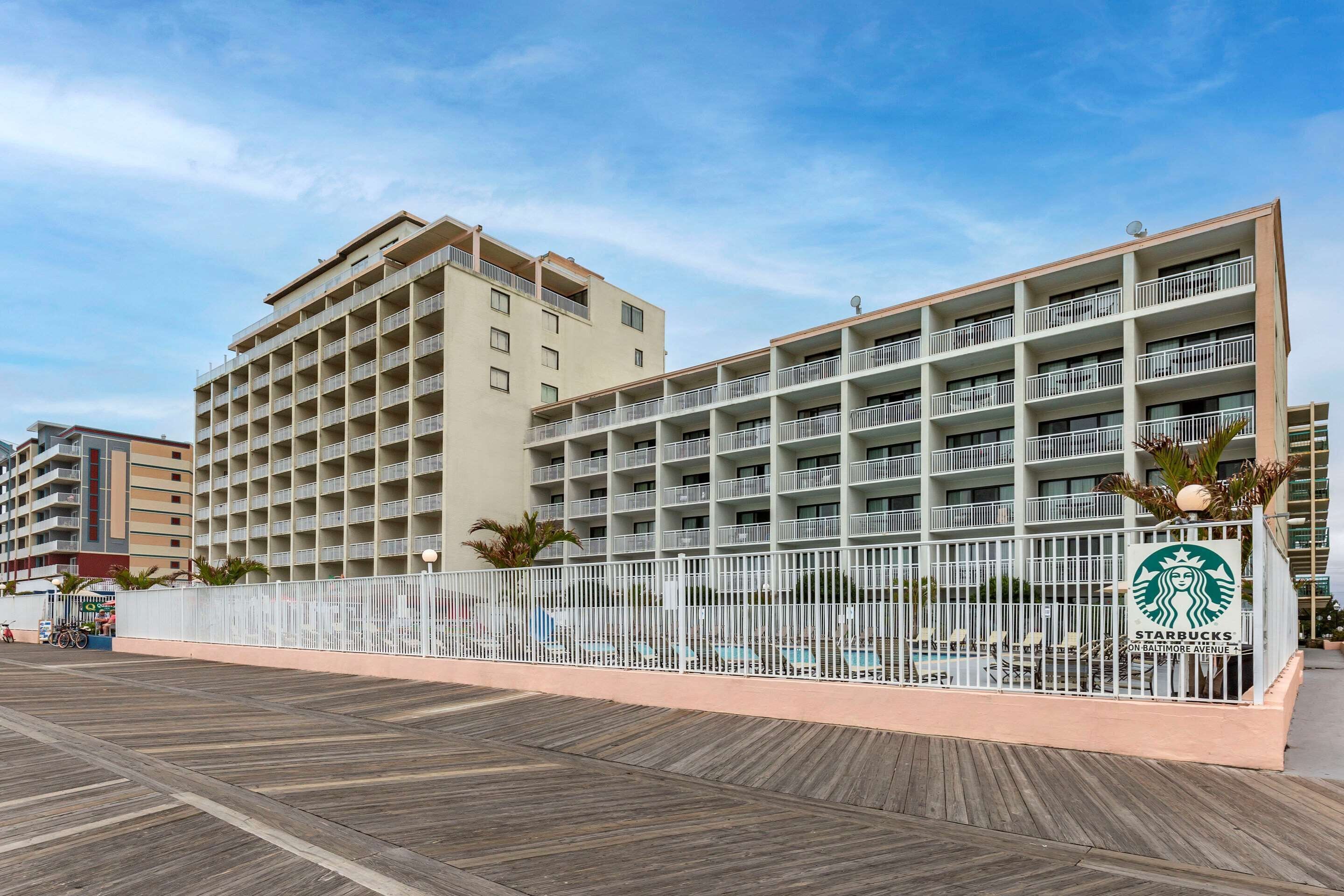 A multi-story hotel with balconies, a pool area, and a Starbucks sign.