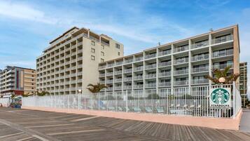 A multi-story hotel with balconies, a pool area, and a Starbucks sign.
