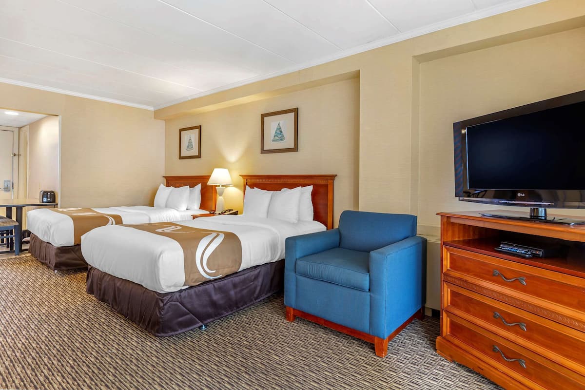 Une chambre d’hôtel avec deux lits, une télévision, un bureau et une chaise.