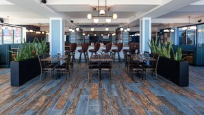 A spacious restaurant with high ceilings, modern lighting, and a mix of seating arrangements including booths and tables. - Quality Inn Boardwalk (Ocean City)