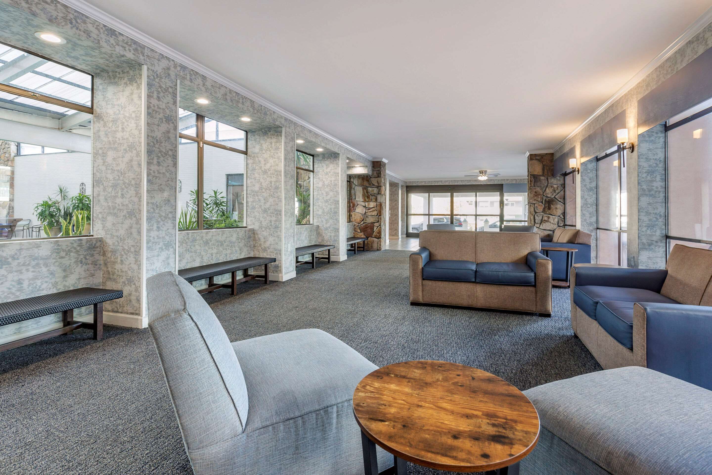 A spacious lobby with high ceilings, large windows, and a mix of seating arrangements including sofas and benches.