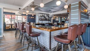 A modern bar area with a central island, bar stools, and hanging pendant lights. - Quality Inn Boardwalk (Ocean City)