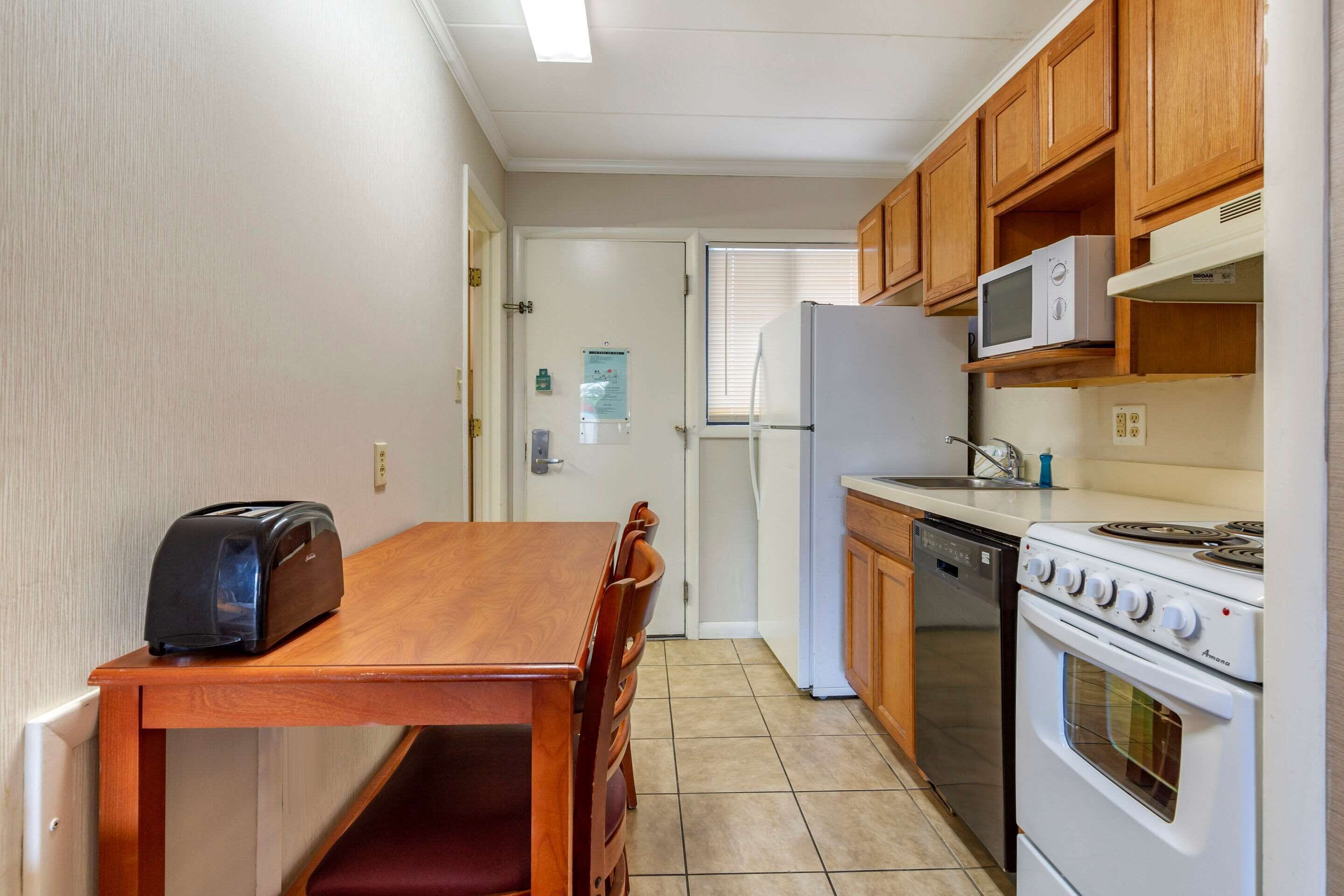 A compact kitchen with wooden cabinets, a microwave, a toaster, a refrigerator, and a stove.