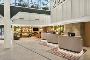 A modern hotel lobby with a reception desk, seating area, and a large window overlooking the outdoors. - Danubius Hotel Bük (Buk)