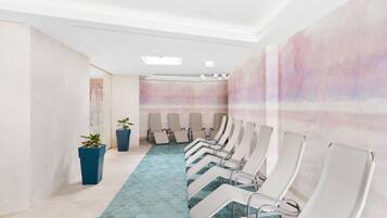 A row of white chairs with metal frames and a blue tiled floor, leading to a wall with a pink and white abstract design.