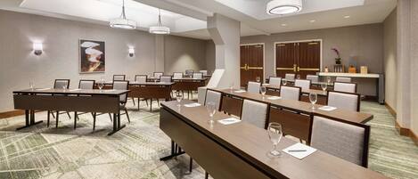 A conference room with long tables, chairs, and modern lighting fixtures.