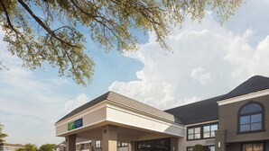 A Holiday Inn Express & Suites hotel with a covered entrance, parking lot, and a clear sky.