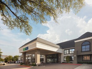 A Holiday Inn Express & Suites hotel with a covered entrance, parking lot, and a clear sky. - Holiday Inn Express & Suites Irving Dfw Airport North by IHG (Irving)