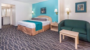 Ein Hotelzimmer mit Bett, Nachttisch, Lampe und einem grünen Sessel.