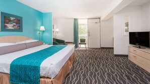 Ein Hotelzimmer mit Bett, Schreibtisch, Fernseher und Blick ins Freie.