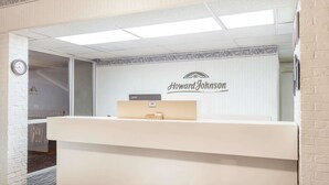 Ein Empfangsschalter mit einem Schild mit der Aufschrift 'Howard Johnson' und einer Uhr an der Wand.