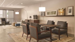 A modern hotel lobby with a seating area, a coffee station, and artwork on the walls. - Country Inn & Suites by Radisson, Port Clinton, OH (Port Clinton)