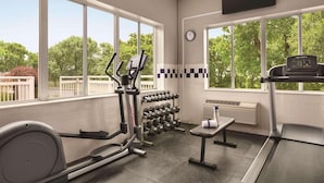 A gym with exercise equipment, a bench, and a TV mounted on the wall. - Country Inn & Suites by Radisson, Port Clinton, OH (Port Clinton)