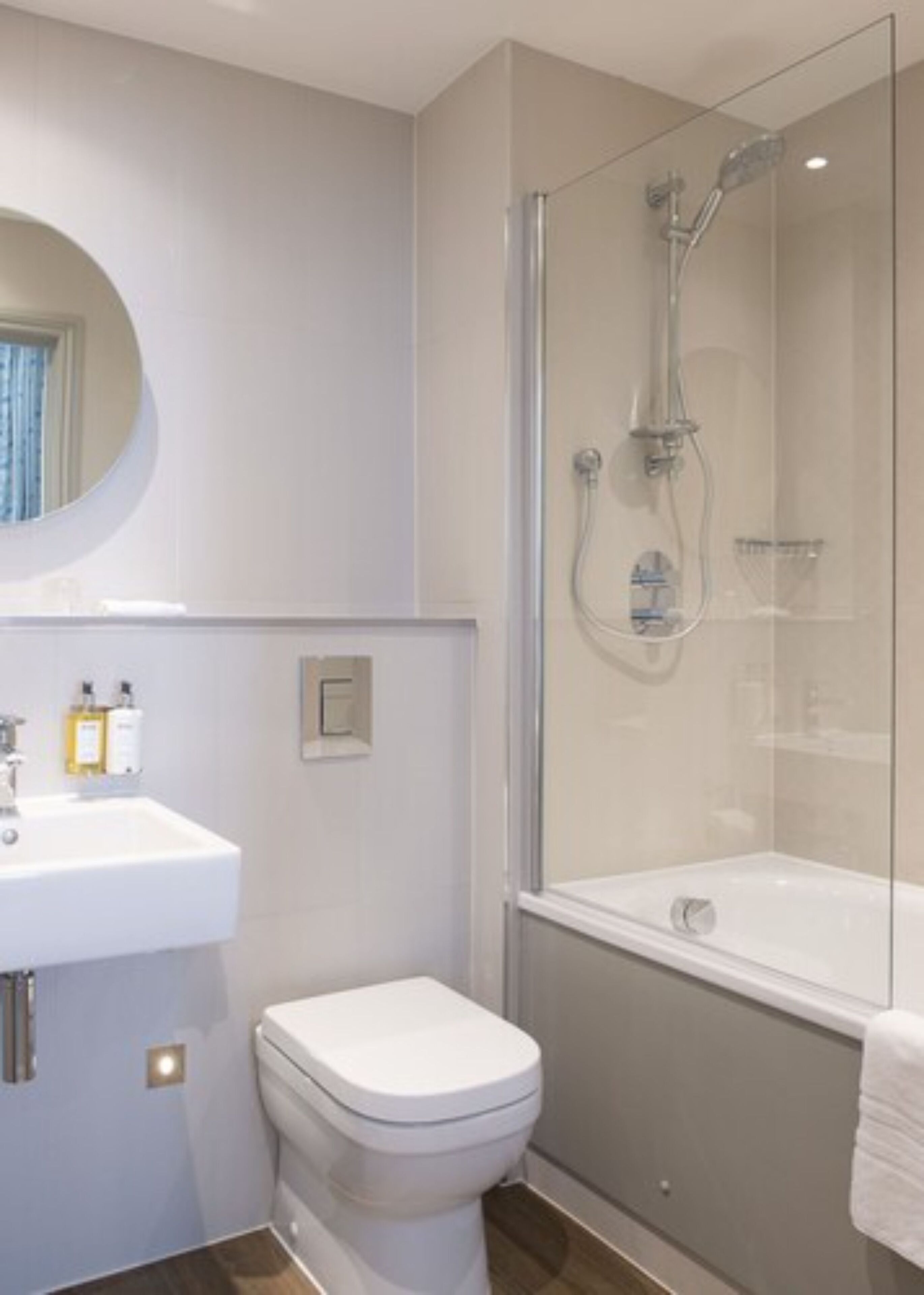 Een moderne badkamer met een douchecabine van glas, een witte wastafel en een toilet.