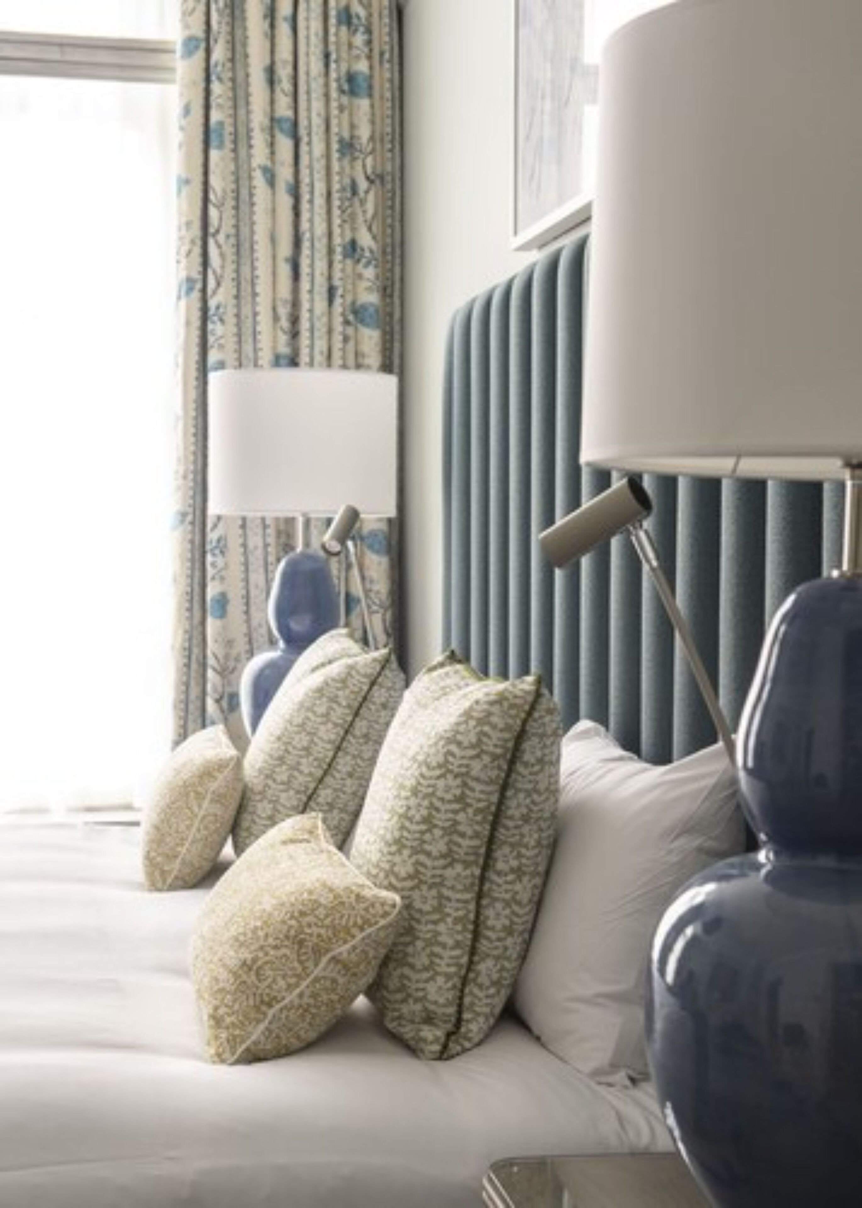 A neatly arranged hotel room with a bed, pillows, a lamp, and a radiator.