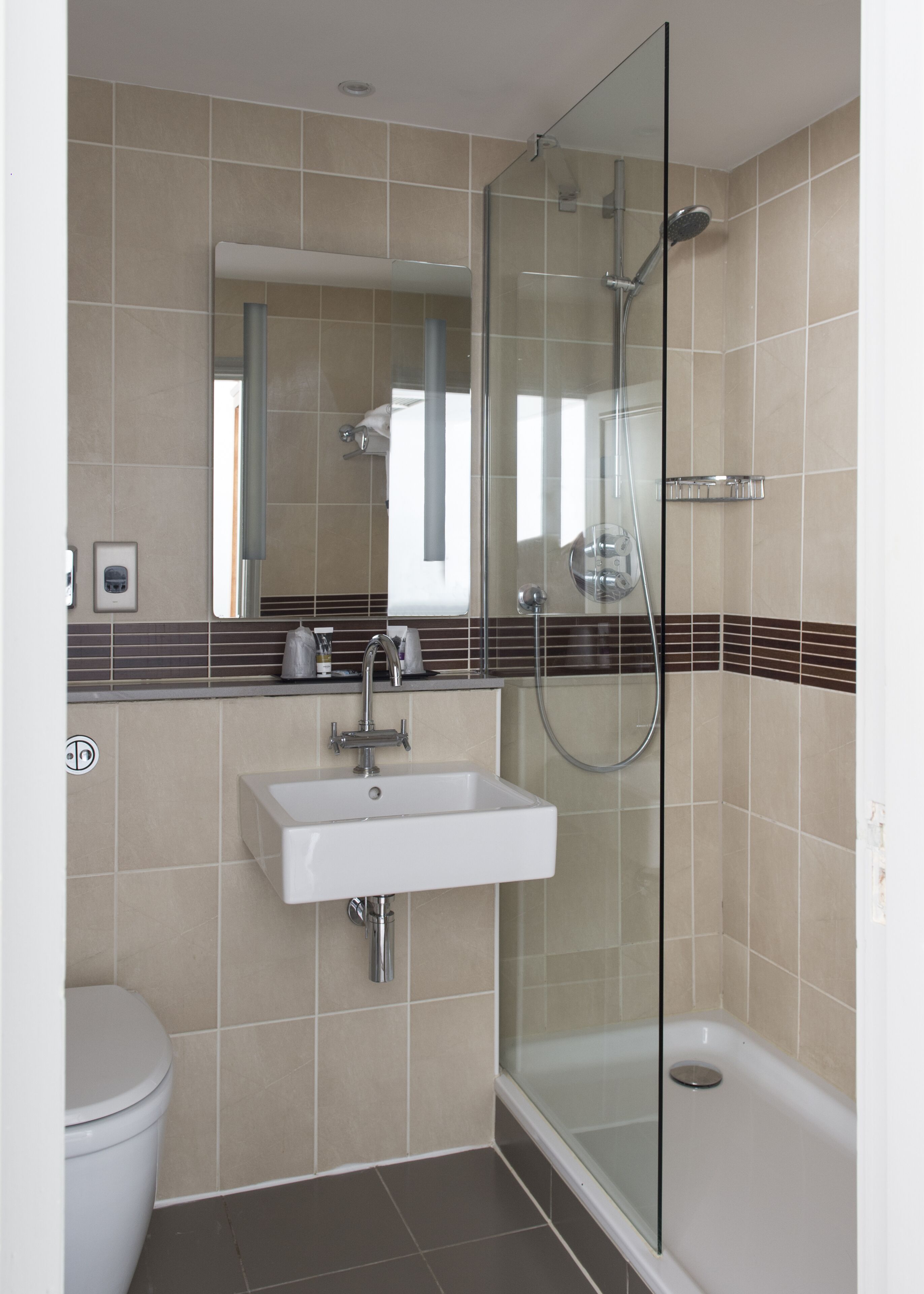 A modern bathroom with a glass-enclosed shower, a white sink, and a toilet.