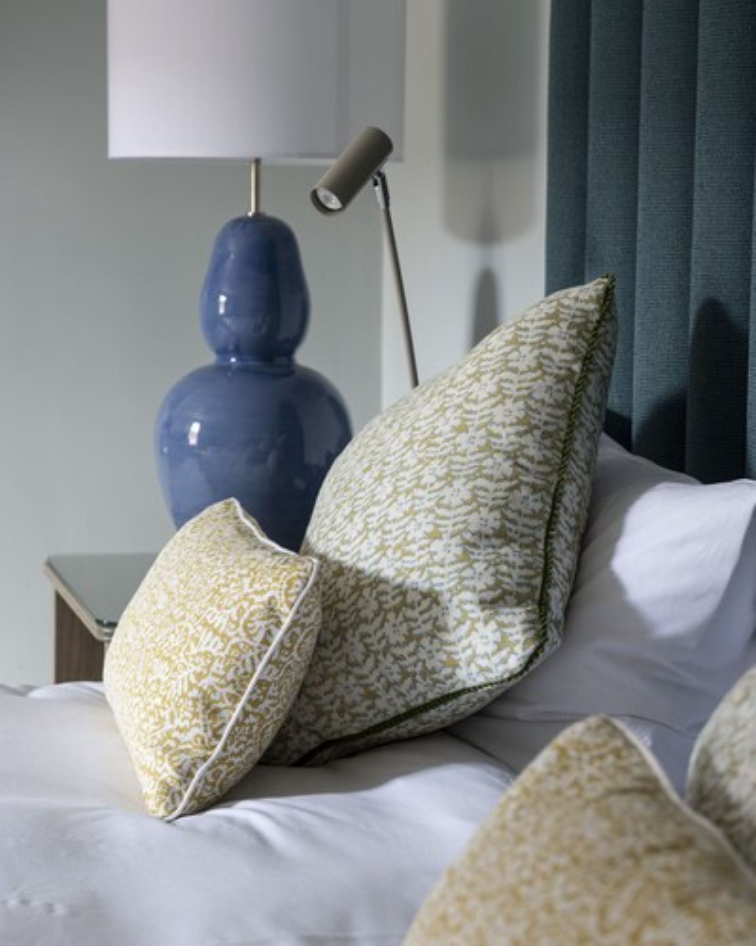 A neatly made bed with white linens and decorative pillows in a hotel room.