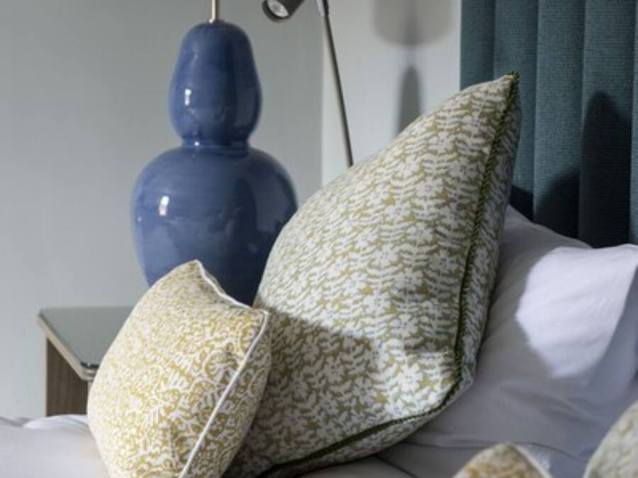 A neatly made bed with white linens and decorative pillows in a hotel room.