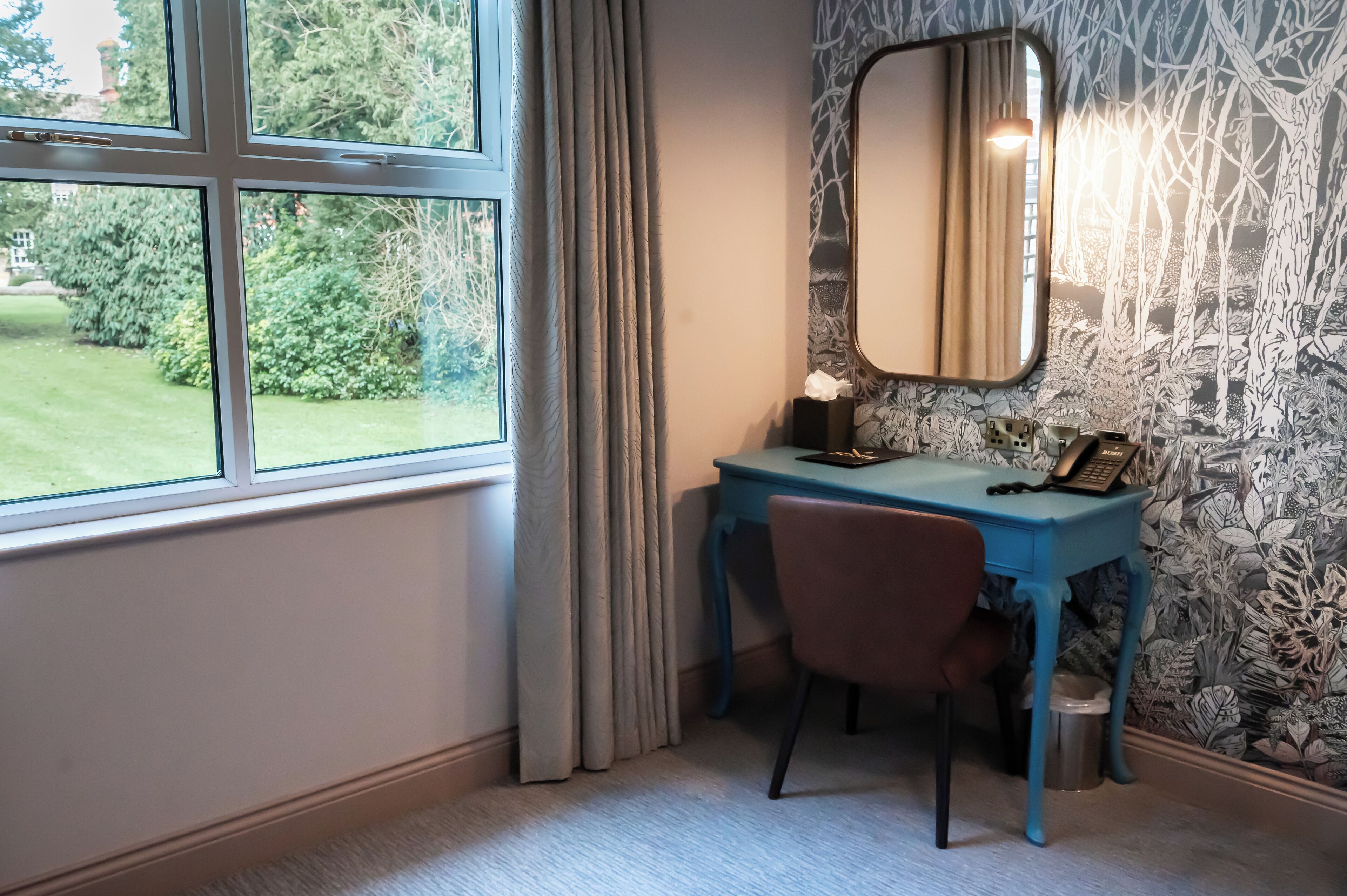 A room with a desk, chair, and a large window with curtains.