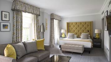 A hotel room with a bed, a sofa, a glass coffee table, and a nightstand with lamps.
