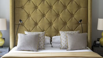 A bed with a tufted headboard, two bedside lamps, and patterned pillows.