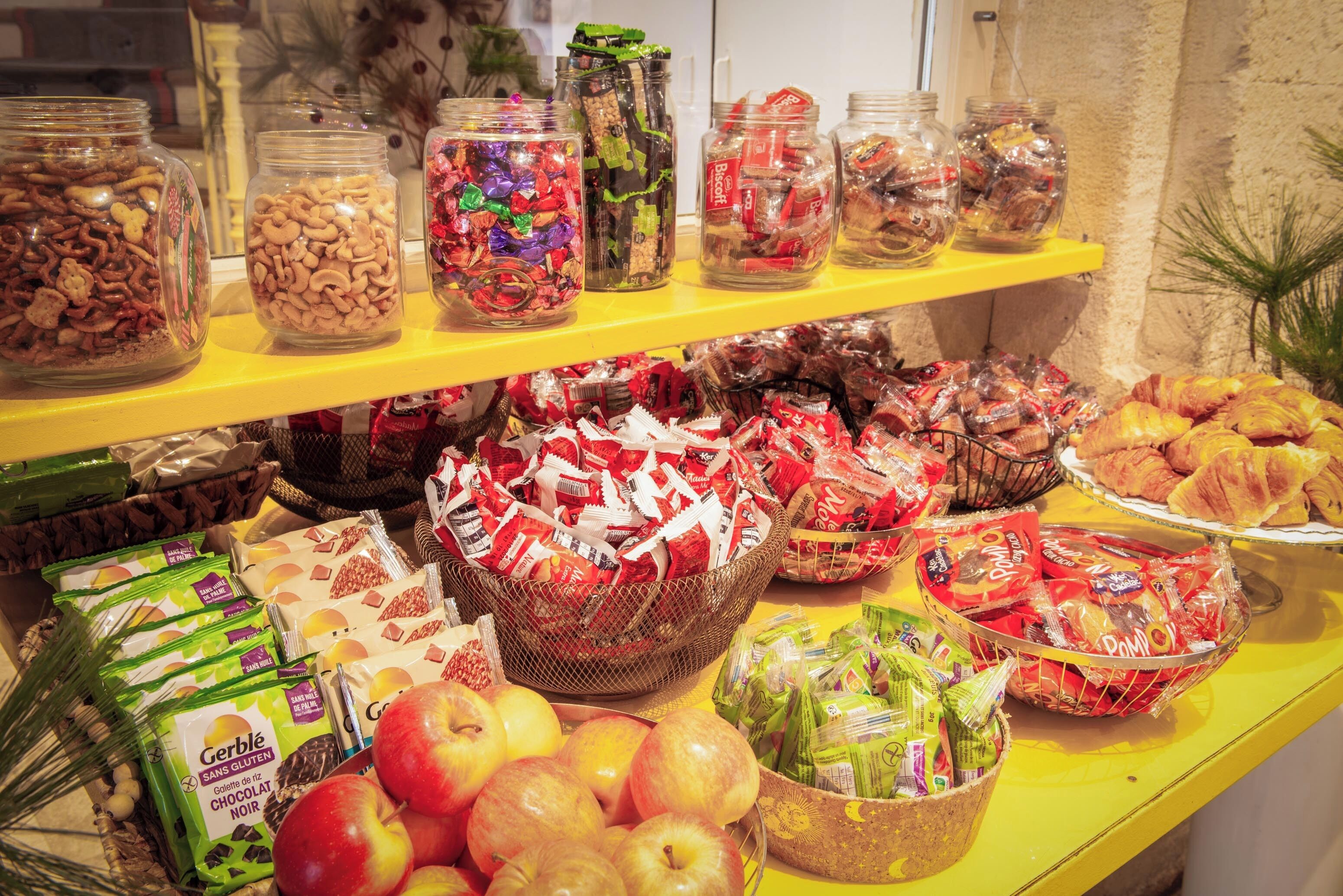 A buffet with various food items including jars of nuts, pastries, and packaged snacks.
