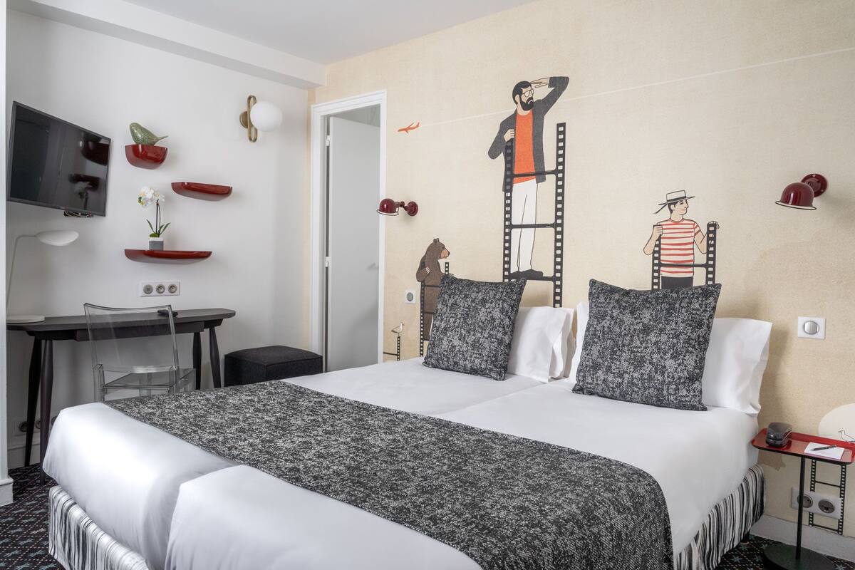 Une chambre d’hôtel avec un lit, un bureau, une chaise et un téléviseur.