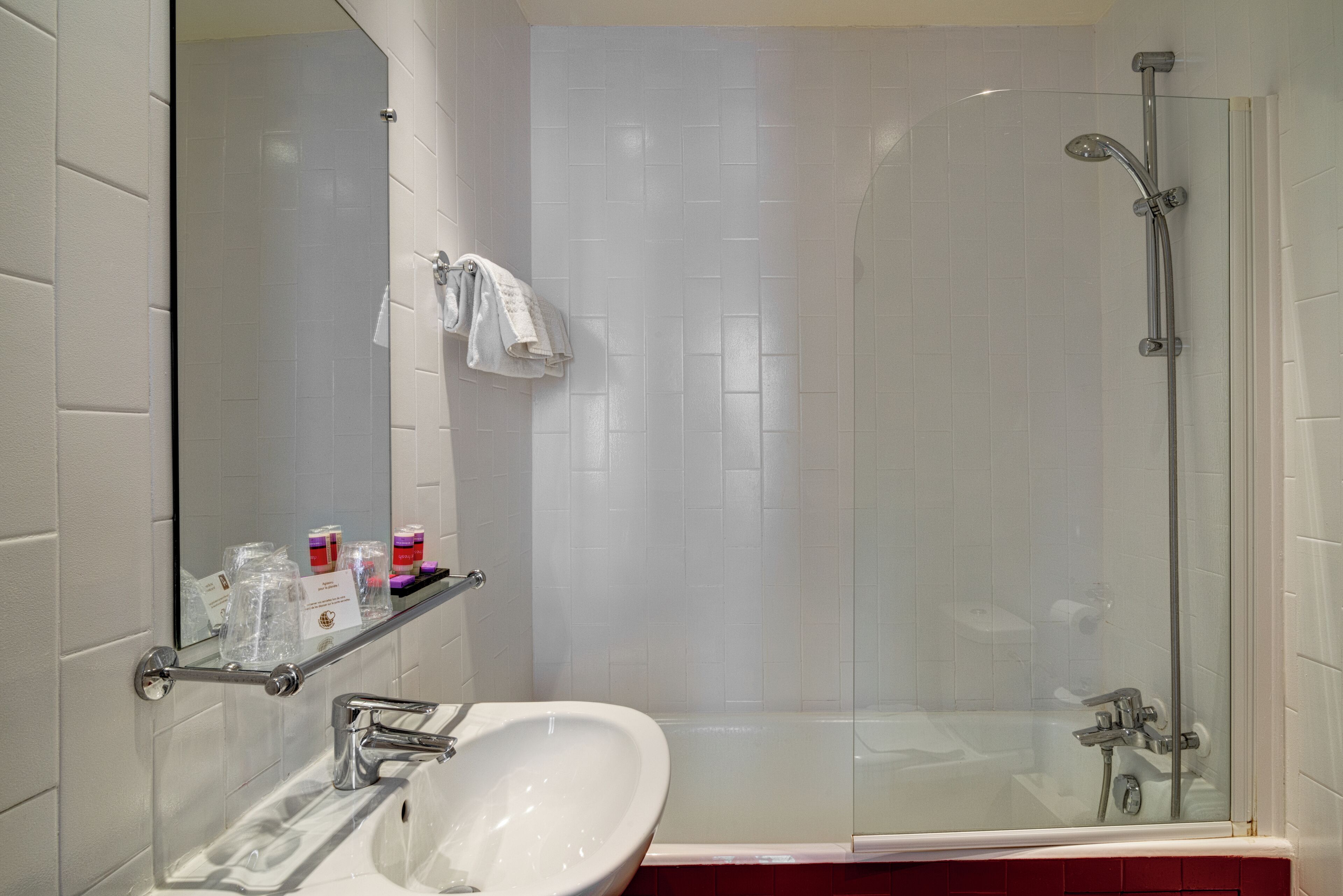 Une salle de bain moderne avec une douche à parois de verre, un lavabo blanc et un miroir au-dessus du lavabo.
