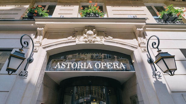 La entrada del Astoria Opera, con detalles arquitectónicos ornamentales y jardineras en los balcones.
