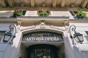 La entrada del Astoria Opera, con detalles arquitectónicos ornamentales y jardineras en los balcones.