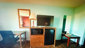 A compact room with a wooden desk, a chair, a television, a microwave, and a refrigerator. - Mayfair Inn (Williamston)