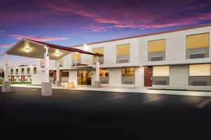 Un hotel moderno con entrada cubierta, varias ventanas y un estacionamiento.