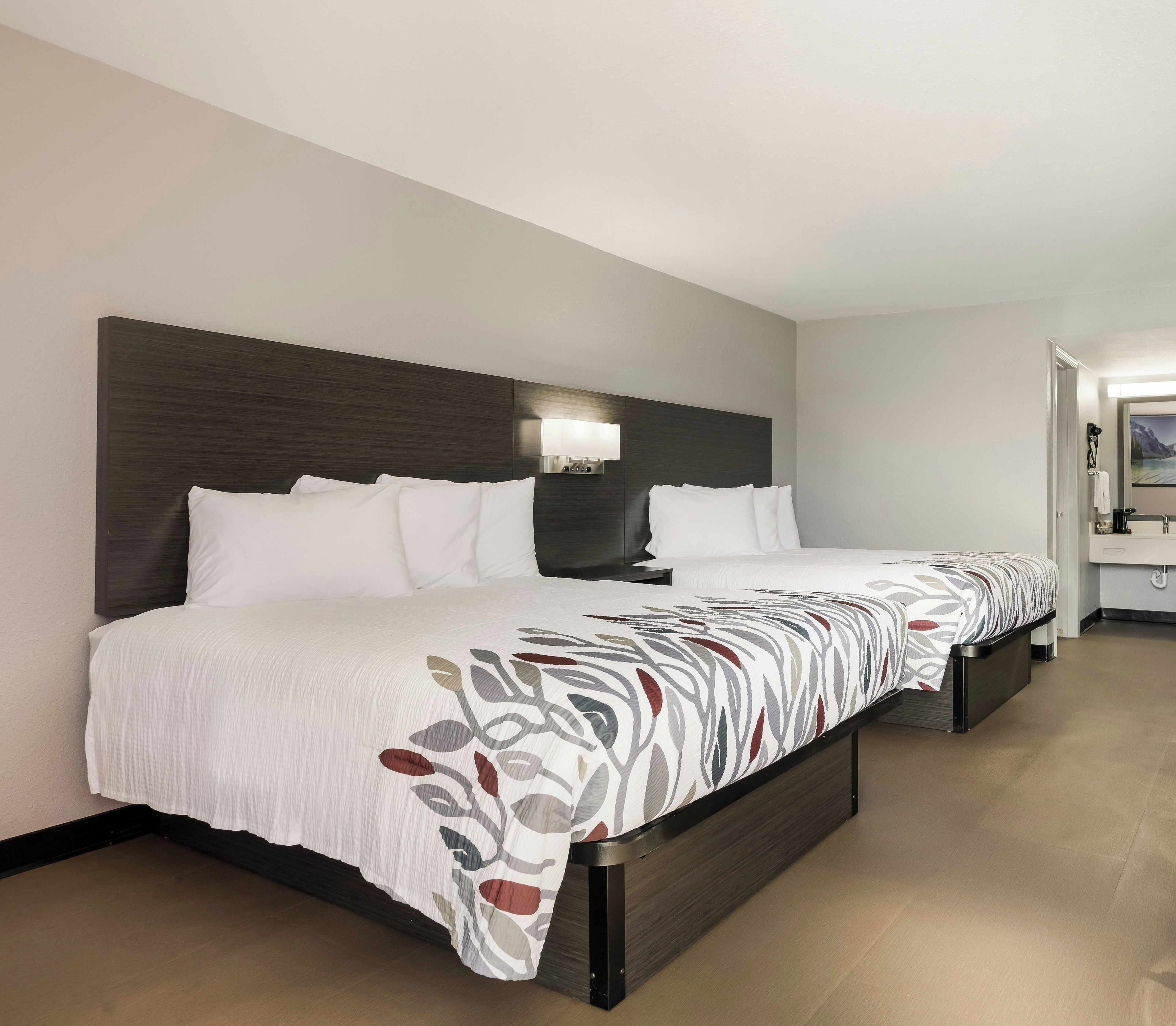 A double bed with a patterned bedspread, a dark headboard, and a bedside table with a lamp.