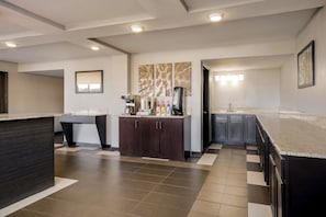 A modern kitchen with a marble countertop, dark cabinetry, and a coffee station. - Red Roof Inn Alexandria, LA (Alexandria)