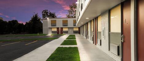 Un edificio moderno con una fila de habitaciones, un césped verde y un estacionamiento.
